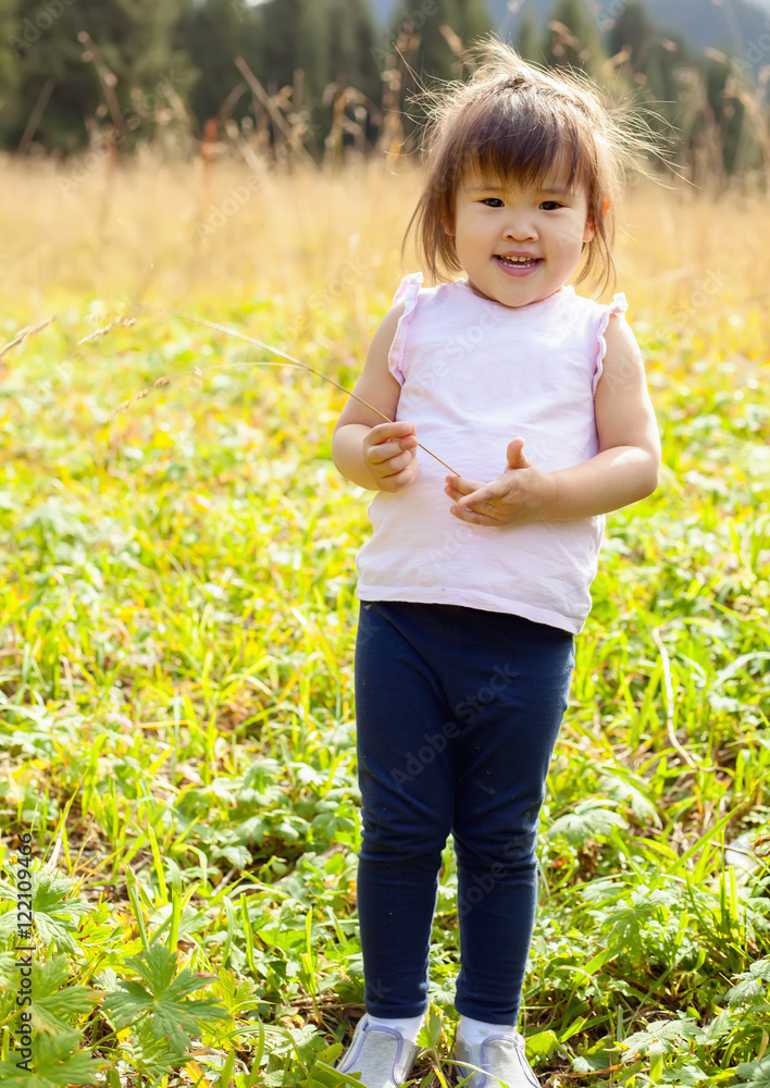 Little asian girl walking on meadow with mountains in the background Little asian girl walking on meadow with mountains in the background