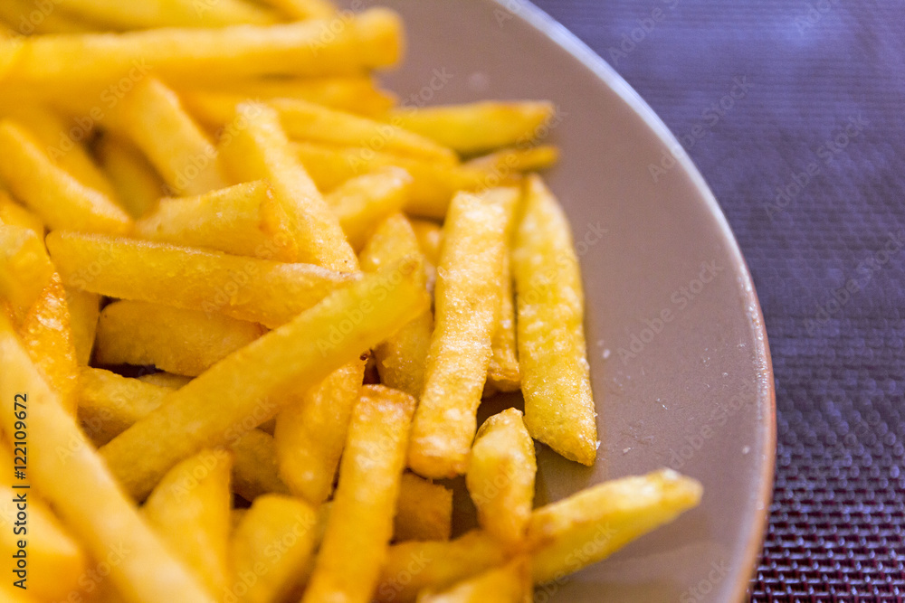 French fries in a brown plate on the coverings French fries in a brown plate on the coverings