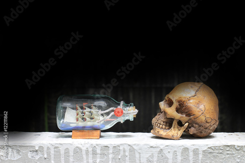 Fototapeta Naklejka Na Ścianę i Meble -  Human Skull with Ship in a Bottle with black background / Still life style