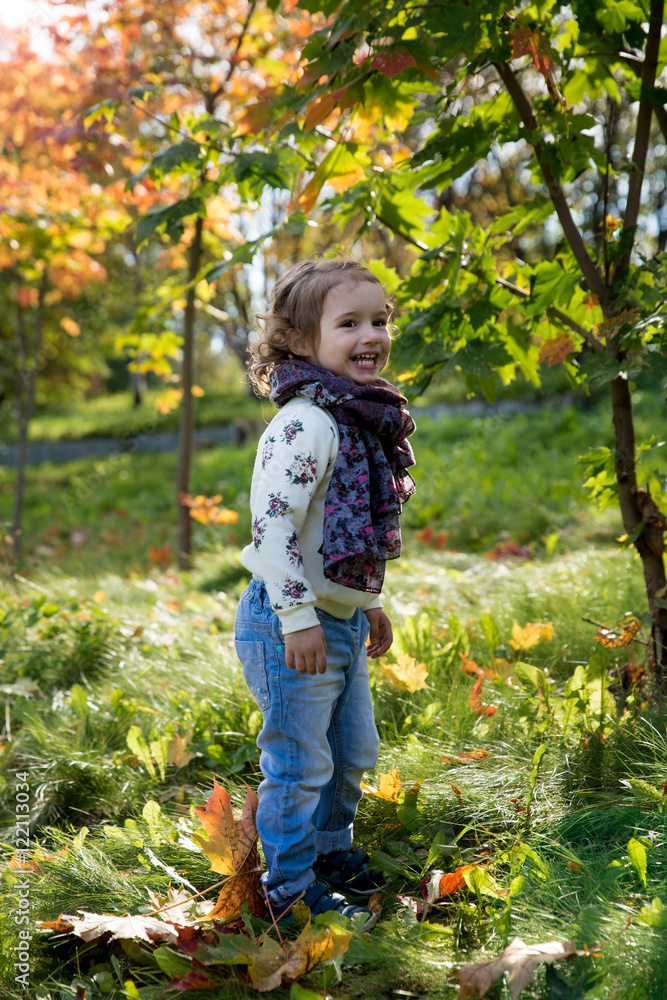 Happy cheerful kid playing in the autumn park. Little girl throwing fallen yellow leaves and laughing. Sunny weather, fresh air. Carefree childhood concept. Healthy lifestyle. Happy cheerful kid playing in the autumn park. Little girl throwing fallen yellow leaves and laughing. Sunny weather, fresh air. Carefree childhood concept. Healthy lifestyle.