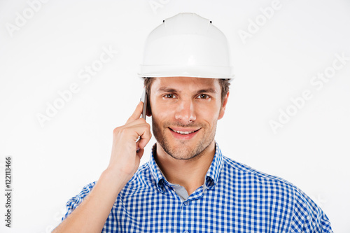 Happy man building engineer in helmet talking on mobile phone