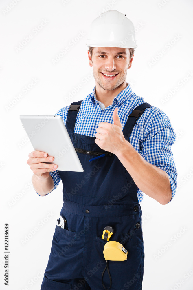 Happy male builder showing thumb up and holding pc tablet Happy male builder showing thumb up and holding pc tablet