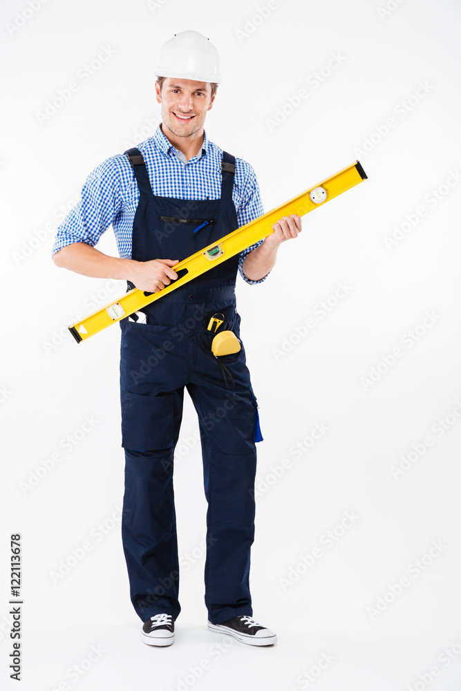 Portrait of a concentrated worker in overalls using level tool Portrait of a concentrated worker in overalls using level tool