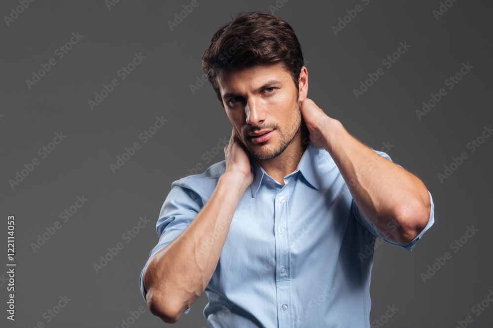 Confident young businessman in blue shirt touching his neck Confident young businessman in blue shirt touching his neck
