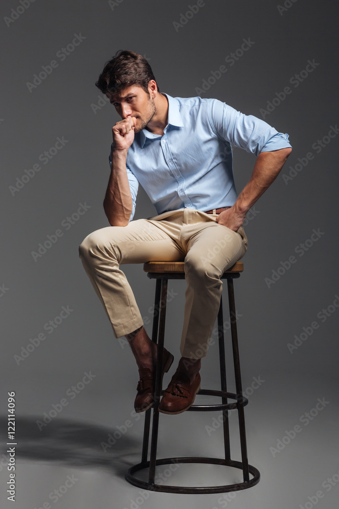 Attractive young man in blue shirt sitting on chair Attractive young man in blue shirt sitting on chair