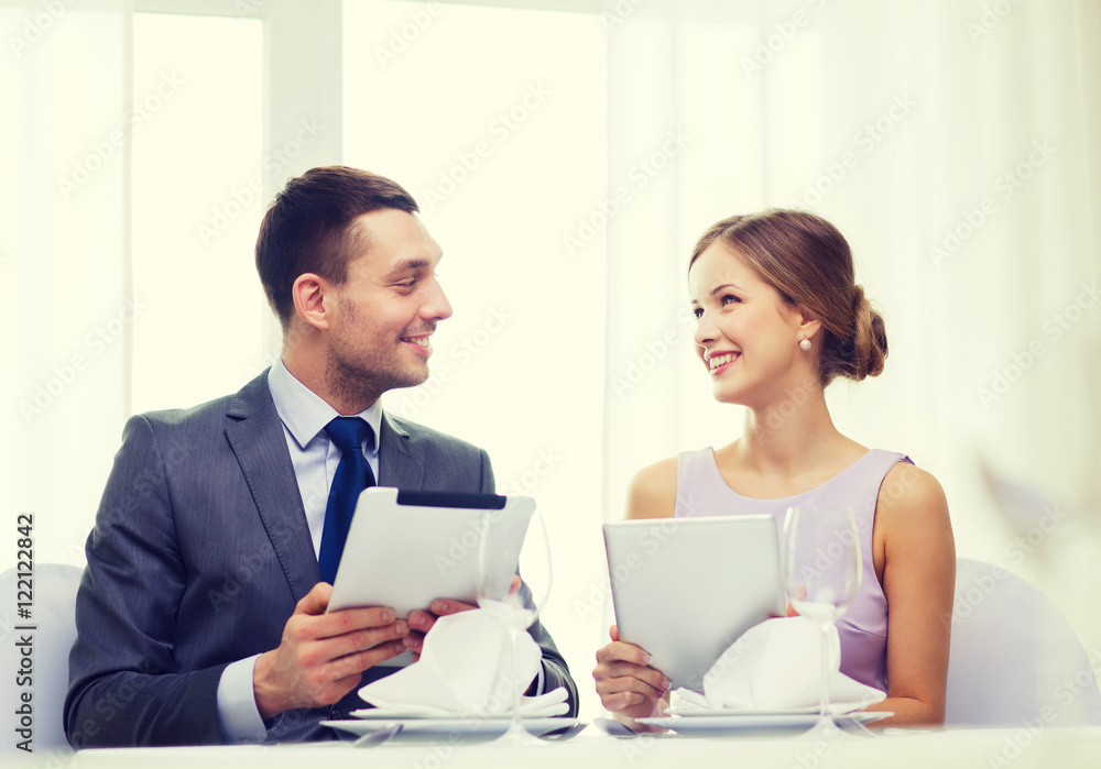 couple with menus on tablet pc at restaurant couple with menus on tablet pc at restaurant