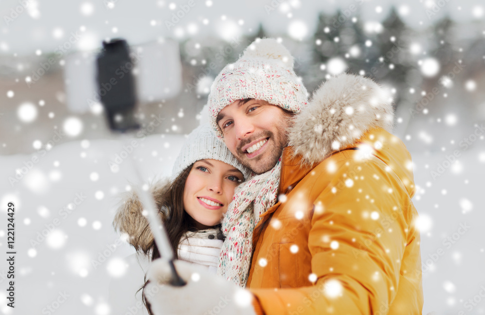 happy couple taking selfie by smartphone in winter