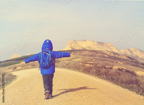 travel concept - little boy hiking on the road to mountains