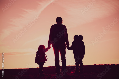 father with two kids travel at sunset