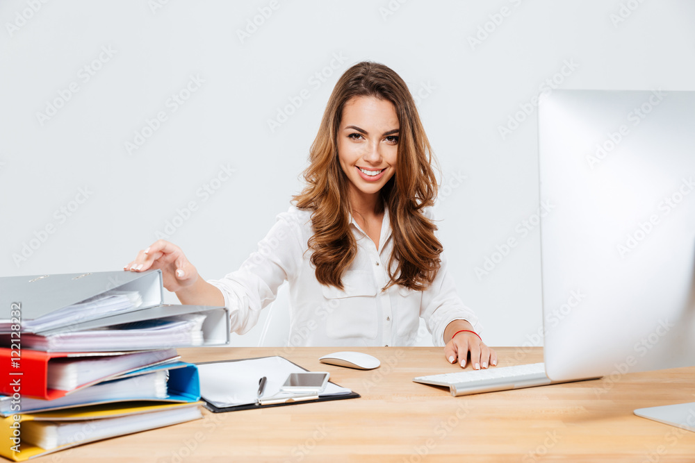 Smiling cheerful businesswoman sitting at her working place Smiling cheerful businesswoman sitting at her working place