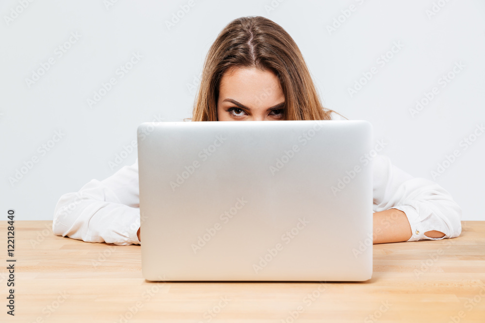 Young brunette woman hiding behind her laptop