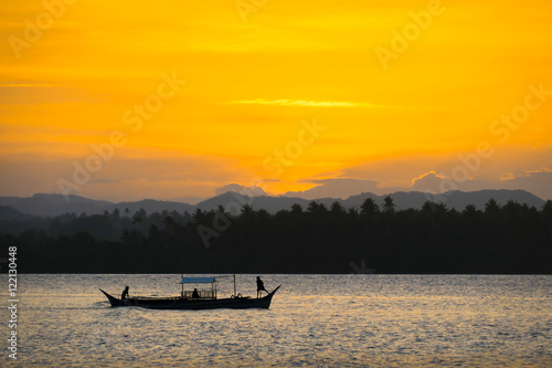 2 Filipino Fishermen Standing on Small Fishing Boat During Orange Island Sunset - Siargao, Philippines