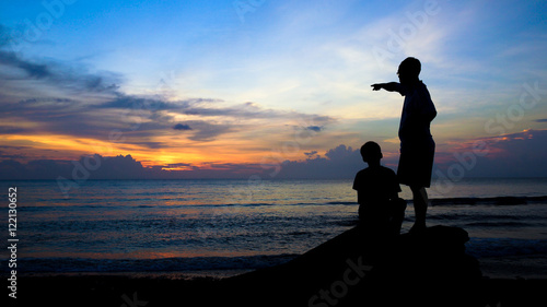 Man Teaching Boy, Silhouette on Beach During Colorful Island Sunset - 