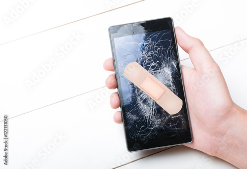 Smart Phone with cracked screen fixed with plaster in hand