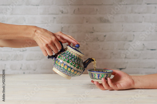 Girl pours tea for man in Asian cafe in teapot