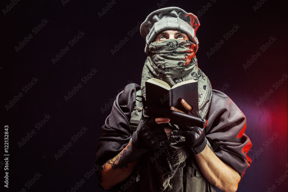 Man reading Quran while holding handgun