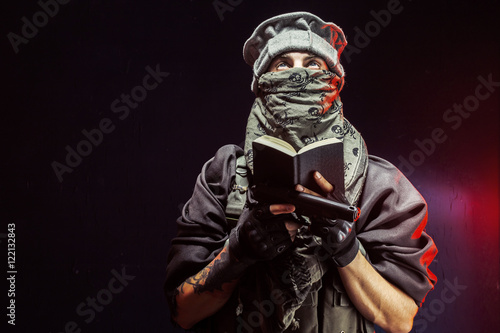 Man reading Quran while holding handgun