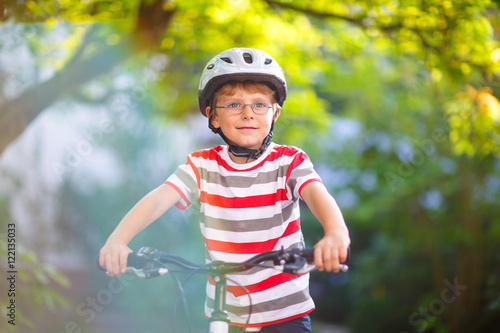 Preschool kid boy in helmet having fun with riding of bicycle