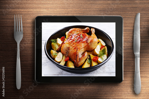 Fototapeta Naklejka Na Ścianę i Meble -  Table appointments and tablet. Photo of food on tablet screen.