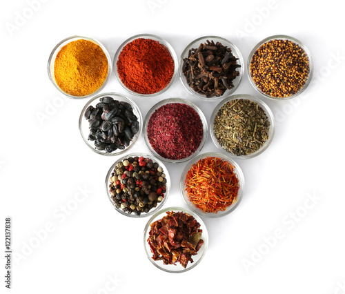 Various spices in glass bowls on white background