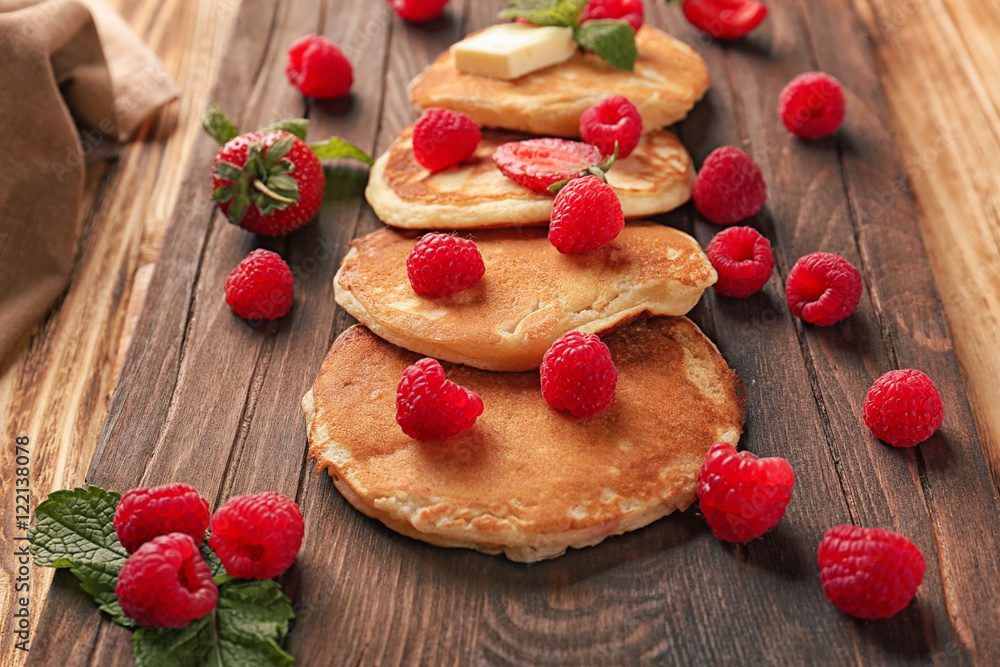 Tasty pancakes with berries, mint and butter on wooden board Tasty pancakes with berries, mint and butter on wooden board