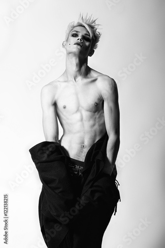 Freaky gothic fashion model boy with blonde hair, piercing and black make up in black mantle
