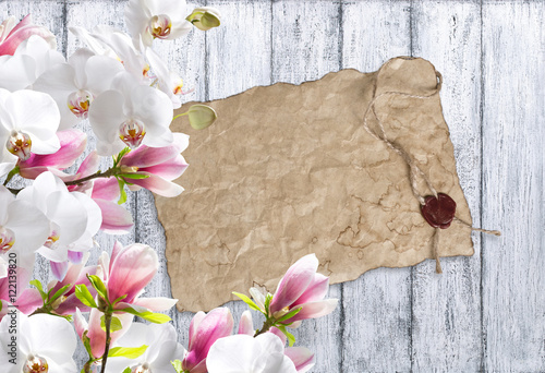 Magnolia with orchid and old paper on background of shabby woode