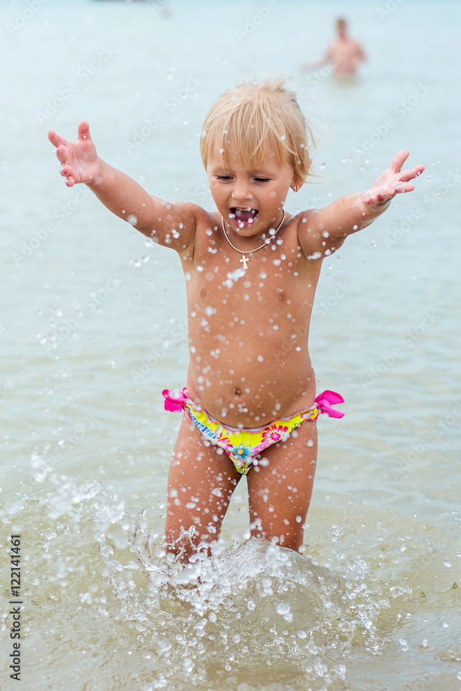 Adorable toddler girl playing with beach toys on white sand beach Adorable toddler girl playing with beach toys on white sand beach