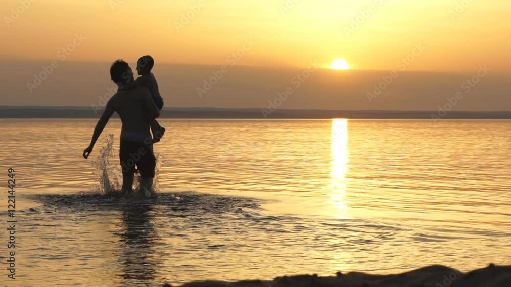 silhouettes of father and son on sunset sea background silhouettes of father and son on sunset sea background