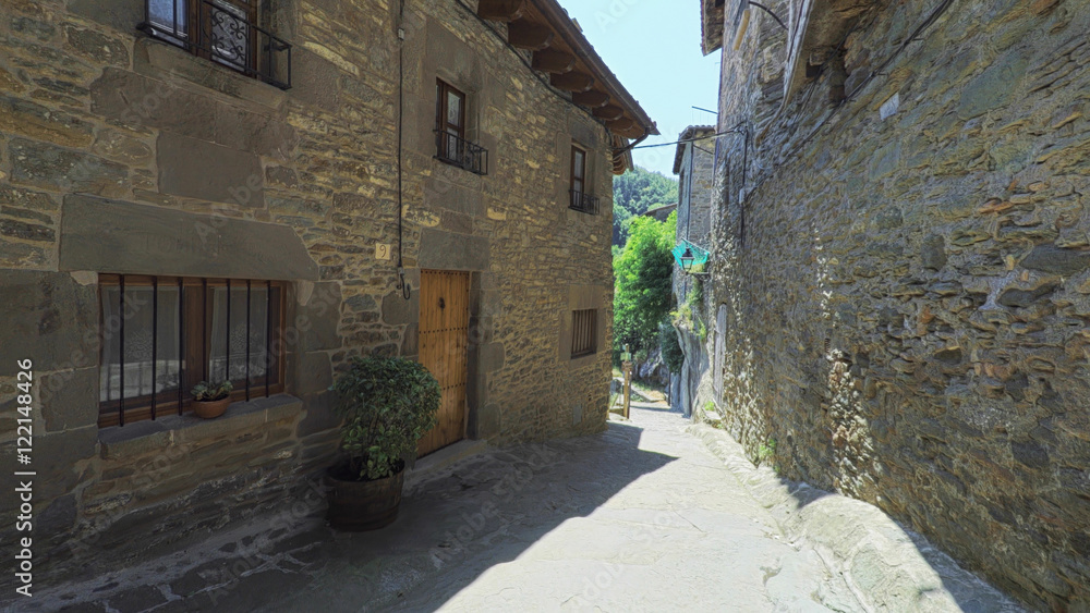 RUPIT CATALONIA SPAIN - JULY 2016: Smooth camera steady wide angle shot along narrow street in the old european spain village goes down, high colorful ancient walls with windows, clear sky with sun