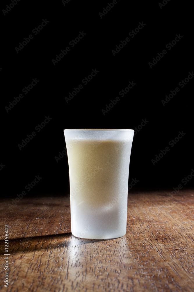 Shot glasses of Brazilian cachaca isolated on rustic wooden background Shot glasses of Brazilian cachaca isolated on rustic wooden background