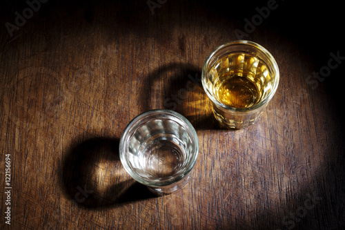 Shot glasses of Brazilian cachaca isolated on rustic wooden background