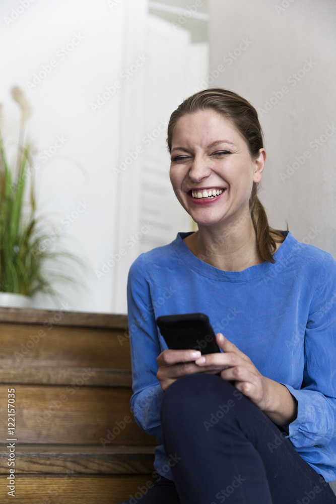 Laughing young woman holding smartphone Laughing young woman holding smartphone