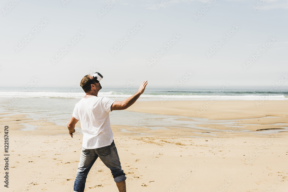 Mature man standing on the beach wearing VR glasses Mature man standing on the beach wearing VR glasses