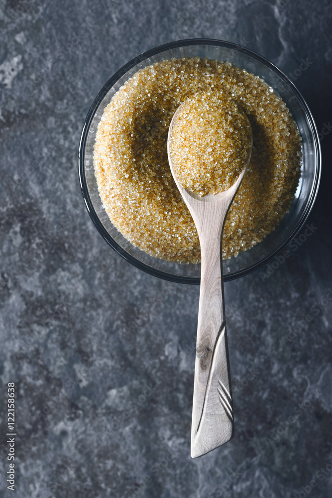 Brown sugar in the glass bowl on the stone background vertical Brown sugar in the glass bowl on the stone background vertical