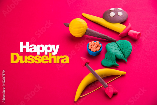 happy dussehra greeting card made using a photograph of colourful clay models of ancient indian armour used in Ramayana and Mahabharata like bow and arrow, sword and shield, gada or gadda, apta leaf photo