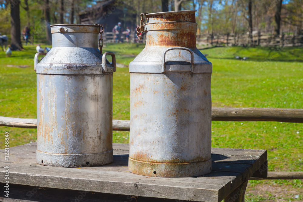 Two metal milk churns on wooden table Two metal milk churns on wooden table