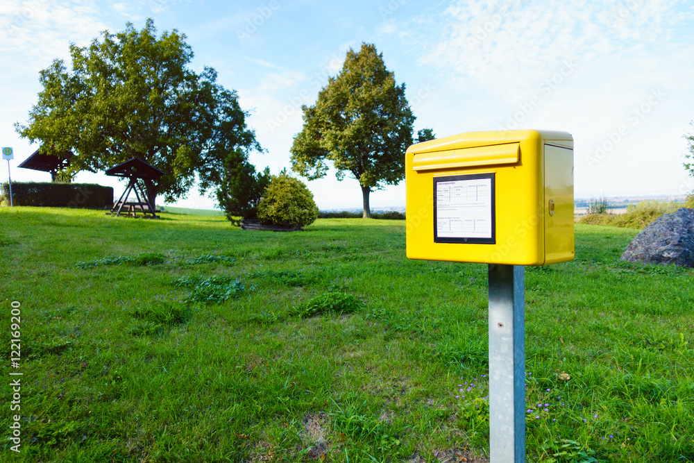 Yellow German postbox one in the green meadow in village Yellow German postbox one in the green meadow in village