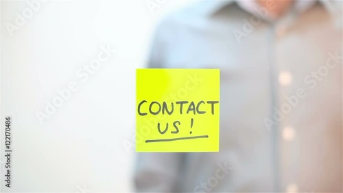 Contact Us. A man sticks a note on transparent screen