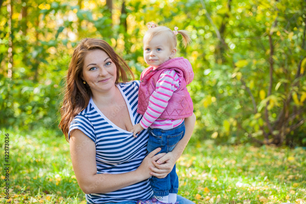 Mom and daughter in the same clothes for a walk in the park in autumn Mom and daughter in the same clothes for a walk in the park in autumn