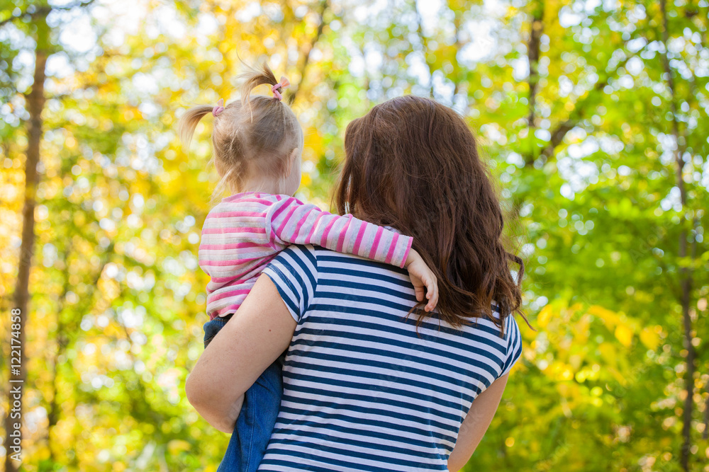 Mom and daughter in the same clothes for a walk in the park in autumn Mom and daughter in the same clothes for a walk in the park in autumn
