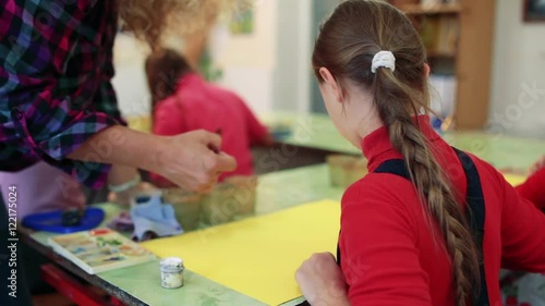 The girl draws a picture paints in classroom photo