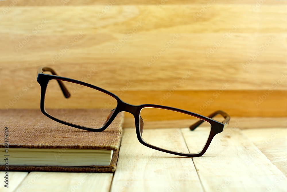 Glasses put brown color notebook on wooden table. Education conc Glasses put brown color notebook on wooden table. Education conc