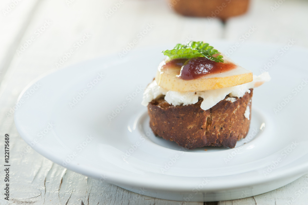 Bruschetta with goat cheese and pear on white plate Bruschetta with goat cheese and pear on white plate
