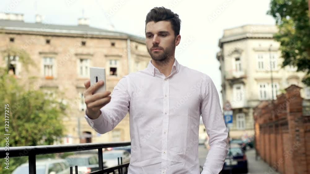 Handsome, stylish man standing in the city and doing selfies on smartphone
Handsome, stylish man standing in the city and doing selfies on smartphone