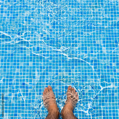 Bare feet cooling off in the pool relaxing concept 