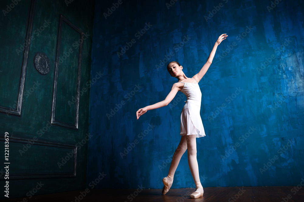 Young teenage ballerina is dancing and posing in the photostudio with blue walls Young teenage ballerina is dancing and posing in the photostudio with blue walls