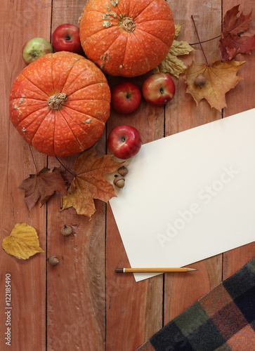 Autumn still life with pumpkins ,leaves and apple on old wooden background, paper place for text