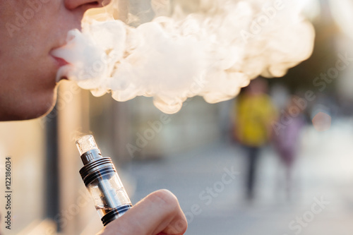man using vape or electronic cigarette against the background of