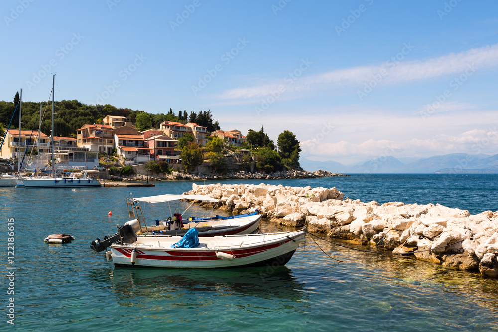 Traditional fishing boats and emerald sea water in Kassiopi port. Corfu Island. Greece.